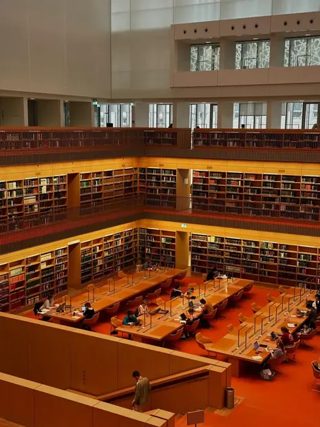 Large university library study hall with students working at desks
